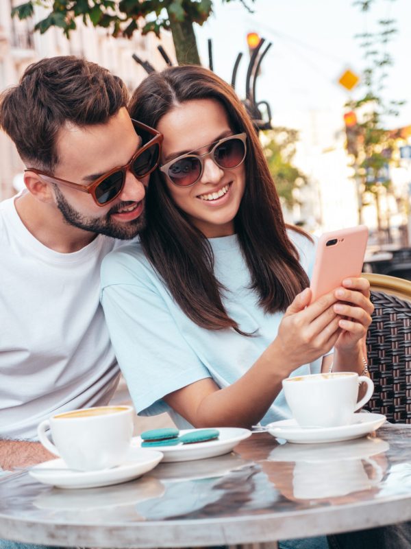 Smiling beautiful woman and her handsome boyfriend. Drinking tea, coffee at veranda cafe outdoors