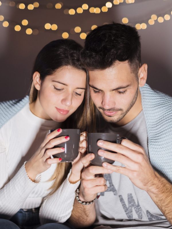 woman-man-coverlet-with-cups-sofa-dark-room